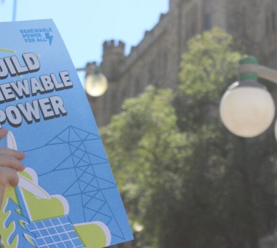 A person at a rally holding a sign saying renewable power for all